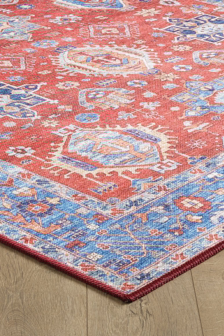 The Lunavale Red Blue Washable Rug (LCC3007) is displayed on a light wood floor, featuring intricate blue, white, and beige geometric patterns with a decorative border—ideal for high-traffic areas.