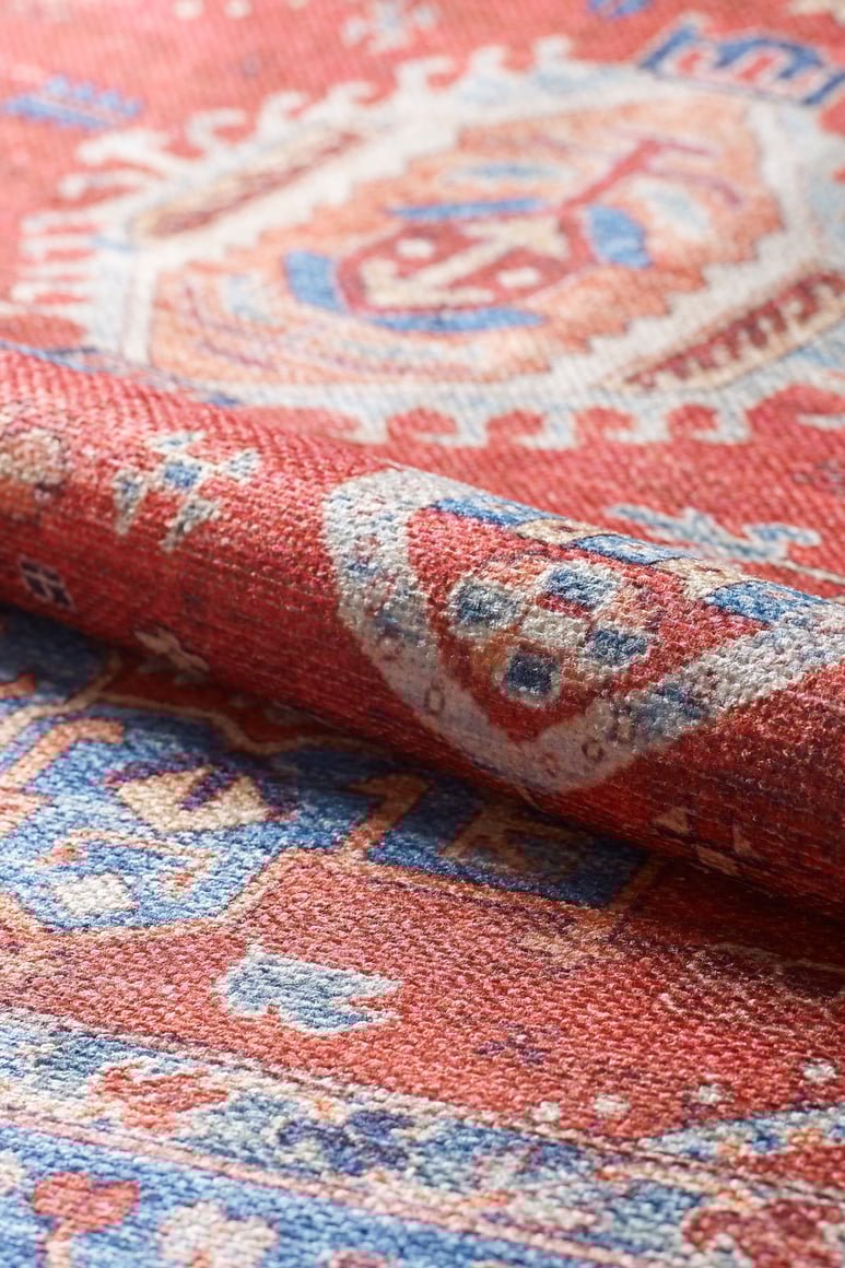 A close-up of the Lunavale Red Blue Washable Rug - LCC3007 shows its intricate blue, white, and beige geometric patterns and textured fabric—perfect as a washable rug for high-traffic areas.