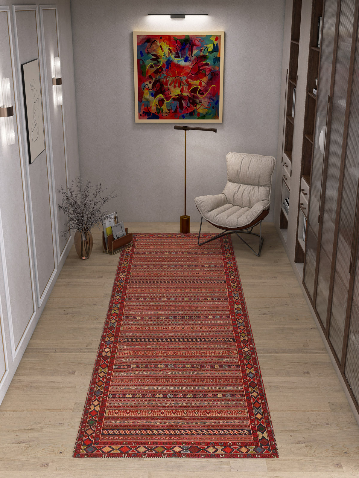 A modern room with light wood floors, a Majestic Loom Washable Rug (JRN1003) in red, a white cushioned chair, floor lamp, glass vase with twigs, colorful abstract painting on the wall, and shelves on the right.