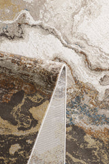 A close-up of the Majestic Marble Premium Area Rug - M673M shows abstract marbled patterns in cream, brown, beige, gray, and blue tones with a folded corner revealing the backside.
