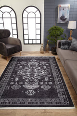A modern living room features wood flooring, a gray sofa, black armchair, indoor plants, decorative vases, large arched windows with white panes, and the Majestic Symbol - Washable Rug - JR1892 (Custom Size) on the floor beneath a painting.
