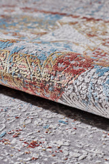 A close-up of the Medallion Remix Colorful Premium Rug - MT120 shows its rolled corner, soft textured surface, and intricate medallion designs in gray, blue, red, and yellow tones with raised decorative details.