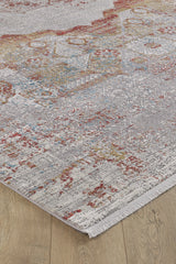 A close-up of the Medallion Remix Colorful Premium Rug - MT120, showcasing its distressed red, yellow, blue, and gray patterns with fringed edges, laid out on a wooden floor.