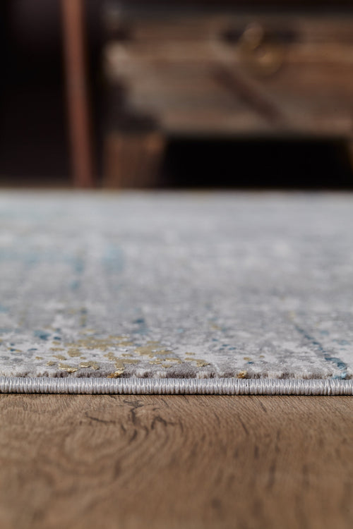Load image 1 in gallery view. A close-up side view of the Medallion Revamp Modernised Medallion Rug - MT002 with a neutral pattern on a wooden floor, highlighting the rug’s edge and featuring a blurred wooden furniture piece in the background.