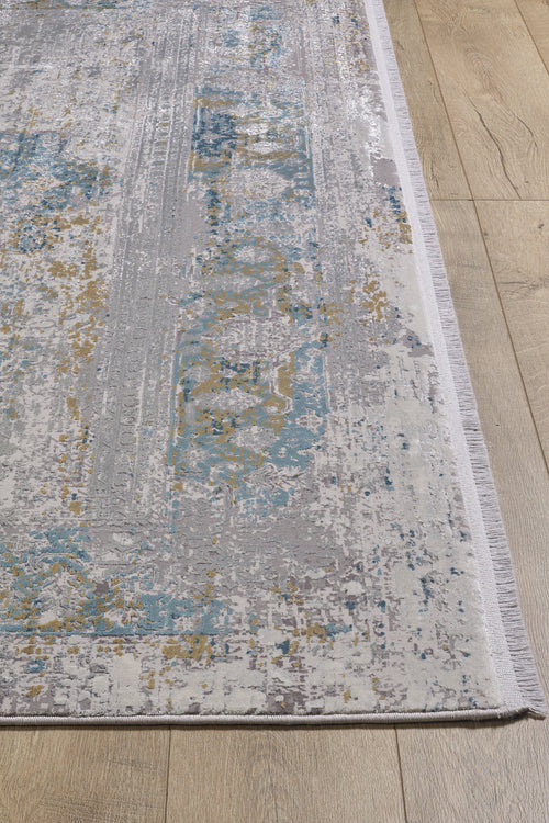Load image 1 in gallery view. A close-up of the Medallion Revamp Modernised Medallion Rug - MT002, featuring distressed vintage patterns in grey, blue, and gold hues on a light wooden floor, with visible fringe along the edge.
