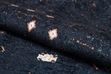 A close-up of the Midnight Majesty - Machine-Washable Rug (JRS5052) showcases black fabric with small white and orange geometric patterns, highlighting its durable weave—perfect for high-traffic areas. Custom sizes available.