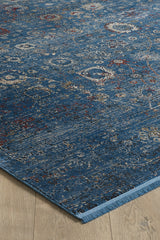 The Miniature Elegance Oushak Rug - Navy - 2084E features intricate, distressed floral and geometric patterns in cream, red, and gold on a blue base. Displayed on light wood flooring, its edge and fringe are visible. Machine-made for lasting beauty.