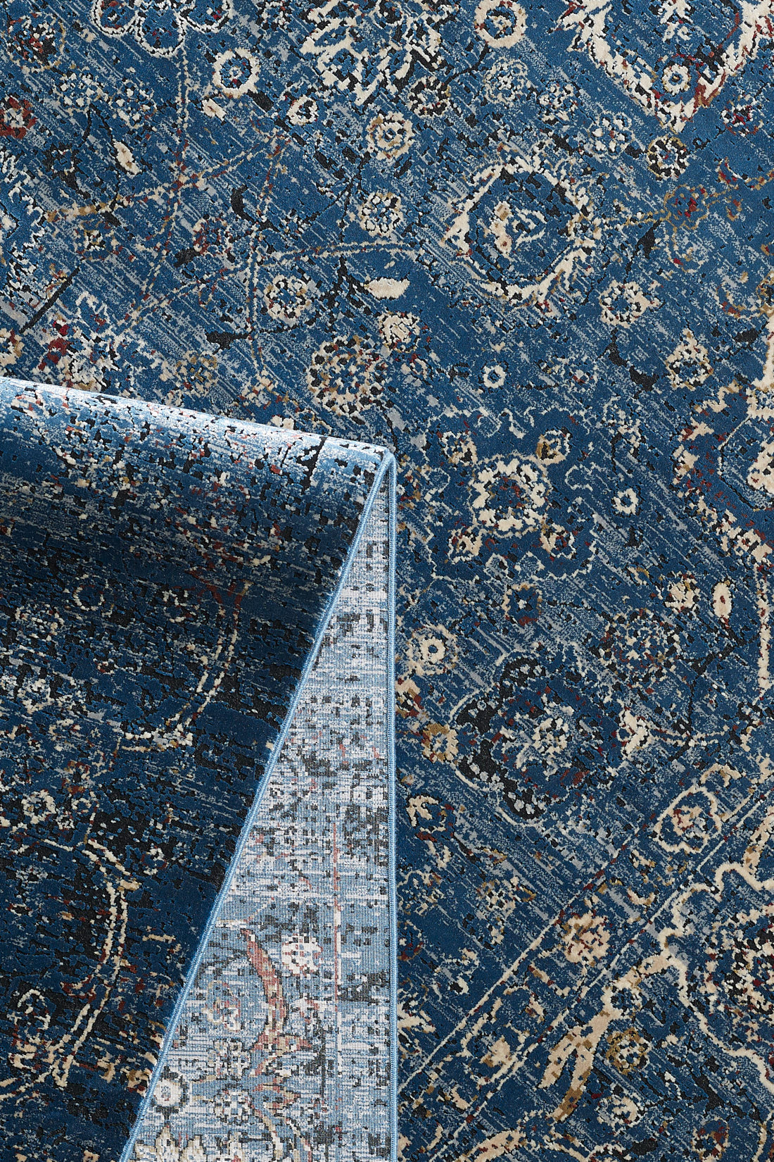 The Miniature Elegance Oushak Rug - Navy - 2084E lies flat with a corner folded to reveal its texture. This machine-made area rug features beige, cream, and red accents in an intricate, vintage-inspired design for timeless appeal.