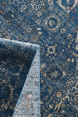 The Miniature Elegance Oushak Rug - Navy - 2084E lies flat with a corner folded to reveal its texture. This machine-made area rug features beige, cream, and red accents in an intricate, vintage-inspired design for timeless appeal.