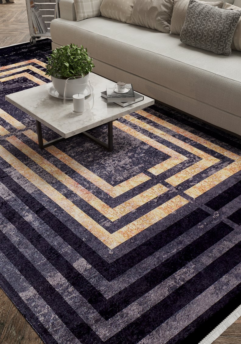 A modern living room features a cream sofa, textured pillows, a marble coffee table with a plant and tray, and the Minimalist and Clean - Washable Rug - JR1407 (Custom Size), perfect for high-traffic areas with its bold geometric pattern.
