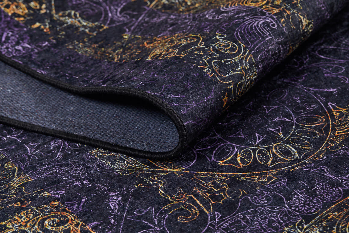 A close-up of the Minimalist and Elegant - Washable Rug - JR1298 shows its intricate gold, purple, and orange patterns. Partially folded to reveal a textured underside, this custom-size rug is perfect for high-traffic areas.