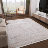 A modern living room with a Misty Mosaic - Washable Rug - JR1690 (Custom Size), beige sofa, wooden armchair, round coffee table with decor, low TV console with books and plants, large window with sheer curtains, and wood flooring.