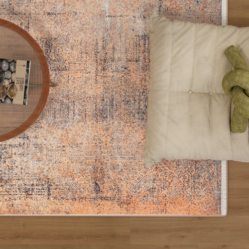 Load image 1 in gallery view. The Modern Mosaic - Machine-Washable Rug JR1846, in a vibrant orange pattern and perfect for high-traffic areas, rests on a wooden floor under a round coffee table with books and a bowl, accented by a cream cushion with a green knitted accessory.