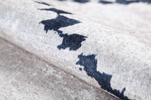 Load image 1 in gallery view. Close-up of the Moroccan Mosaic - Washable Rug - JR1655 (Custom Size) in beige, featuring a soft texture and abstract dark navy blue pattern. Slightly rolled to showcase its plushness, it's perfect for high-traffic areas with stylish appeal.