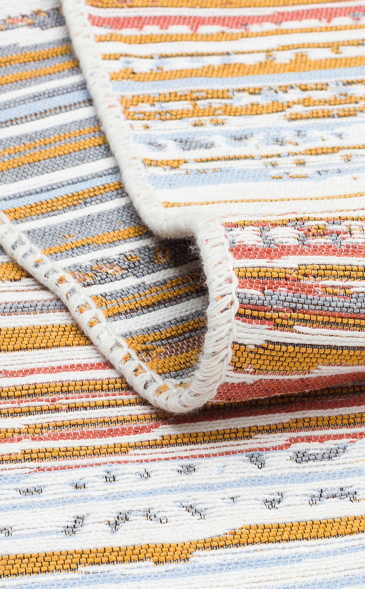 A close-up of the Mosaic Fade - Washable Reversible Kilims - AR35 shows a folded corner and horizontal stripes in mustard yellow, rust orange, light blue, white, and gray. Flatwoven with visible edge stitching for extra detail.