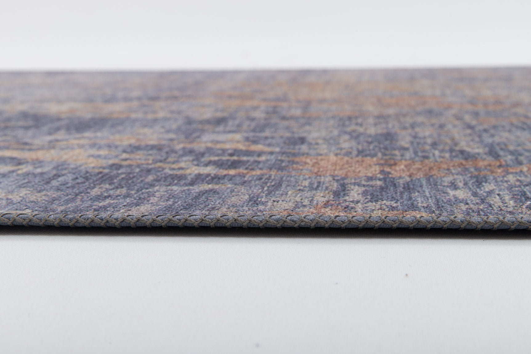 Close-up side view of the Mystical Mosaic - Washable Rug - JRS003 (Custom Size), a thin, rectangular rug in blue, beige, and brown with textured surface and detailed edge stitching, ideal for high-traffic areas.