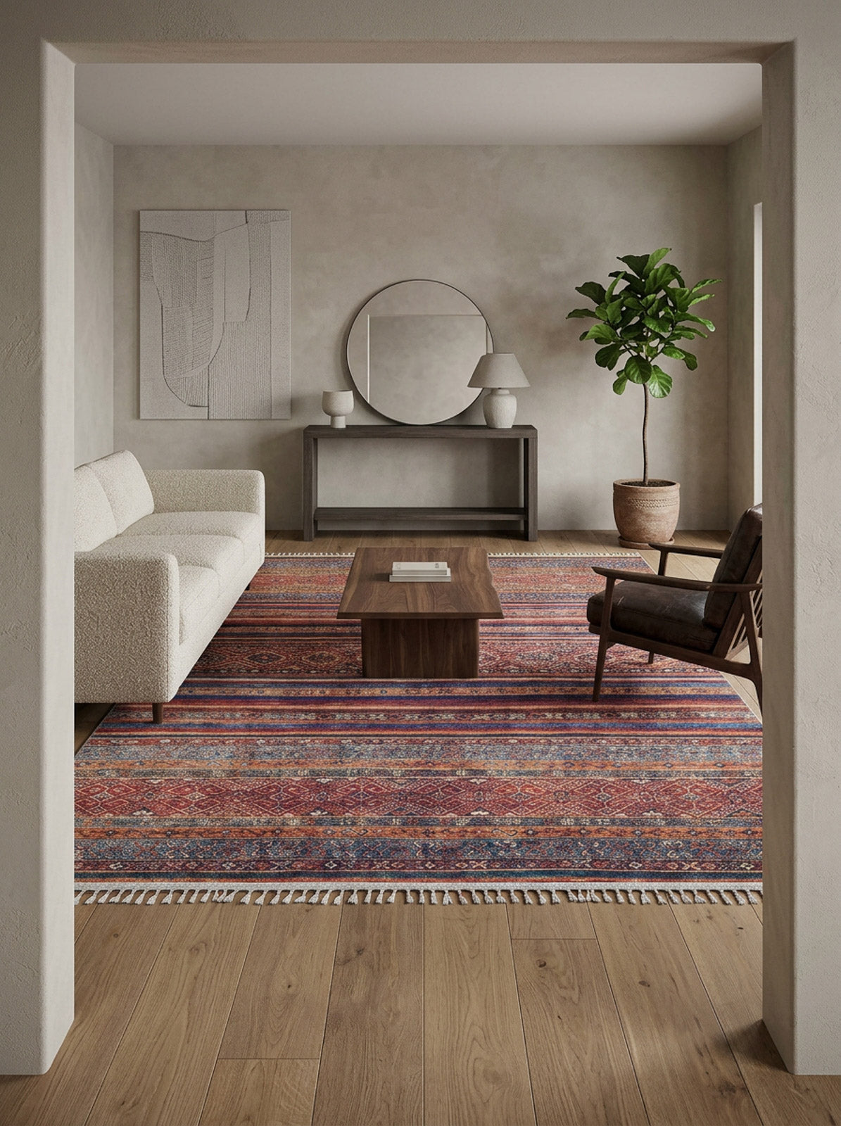 A modern living room with a white sofa, dark armchair, wooden coffee table, and the Native Nightscape - Washable Rug - JR5093. The space includes a potted plant, round mirror, minimalist wall art, a console table, and neutral-toned walls and floor.