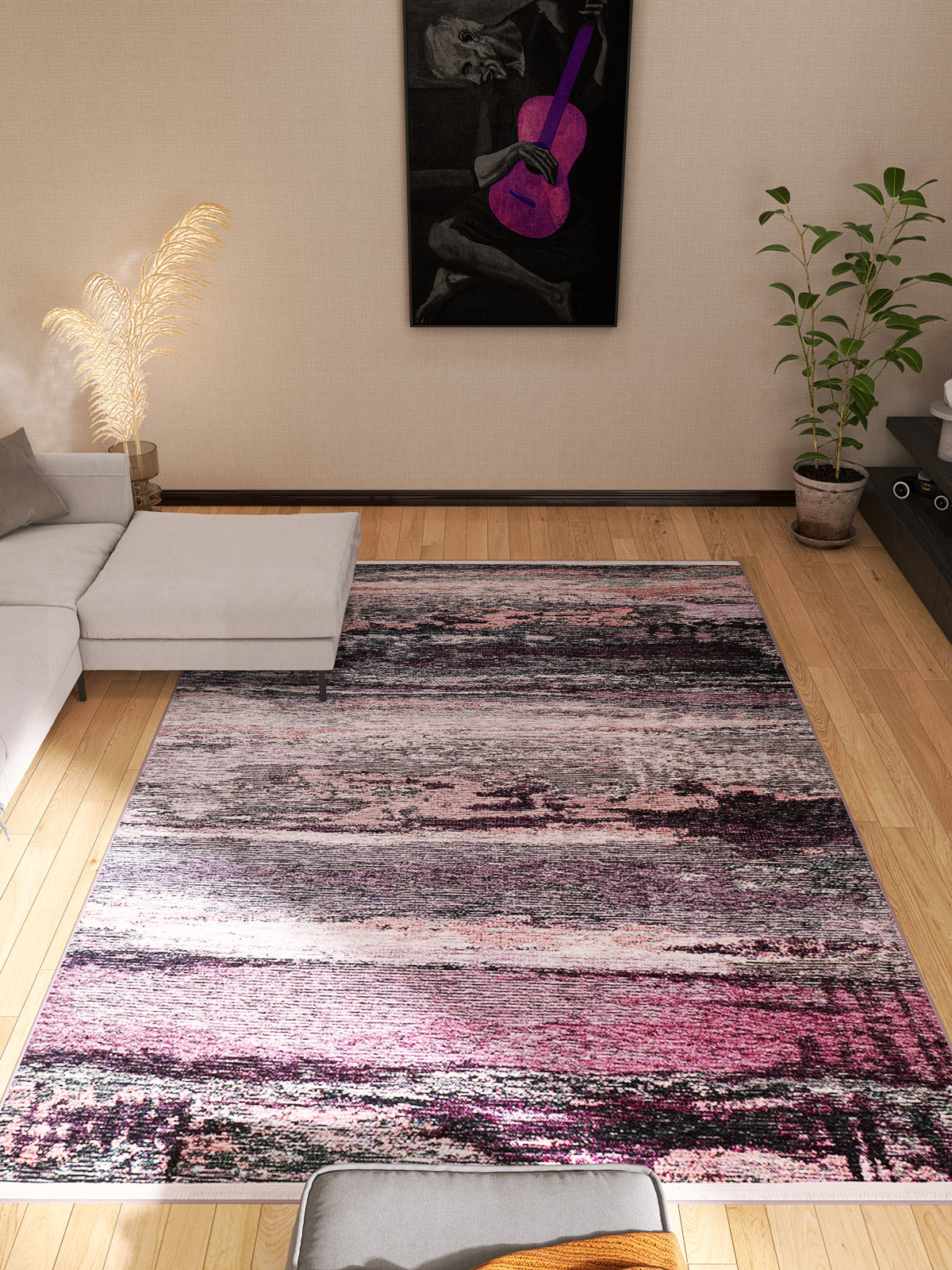 A modern living room with a light gray sectional, the Natural Brushed - Washable Rug - JR336 (custom size), a potted plant, and purple guitar wall art. Warm lighting and wooden floors make it cozy and ideal for high-traffic areas.