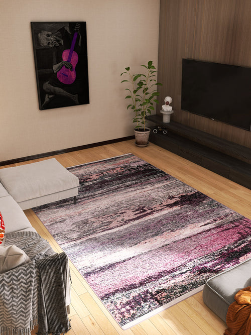 Load image 1 in gallery view. A modern living room with the Natural Brushed - Washable Rug - JR336 (Custom Size) in pink, gray, and black on wood floors, alongside a sectional sofa, potted plant, TV on a wood-paneled wall, and purple guitar artwork—perfect for high-traffic areas.