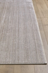 The Neutral Frame Modern Bordered Rug - EW5541, in light beige with subtle textured stripes and a fringed edge, adds a minimalist touch to the wooden floor. This machine-made rug features a soft, faded pattern for modern appeal.