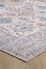 The Nexa Bordered Beige Washable Rug (LCC3009) features cream and beige tones with blue, gray, and beige geometric and floral patterns, a decorative border, and a distressed vintage look on a flat woven surface.