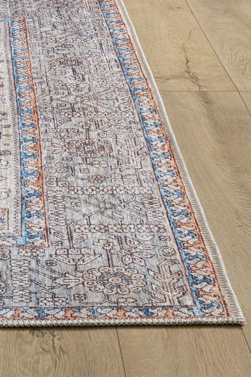 Bild 1 in Galerieansicht laden. A close-up of the Nexa Bordered Beige Washable Rug - LCC3009 (Custom Size) shows its intricate floral and geometric patterns in blue, gray, and beige with orange-accented borders, laid on a light wood floor—perfect for high-traffic areas.