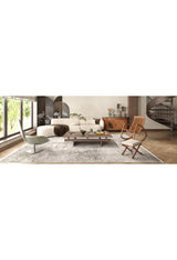 Modern living room with a white sectional, wooden coffee table, two stylish chairs, large windows, and the Noble Insignia - Washable Rug - JR1830—perfect for high-traffic areas. Decorative plants and a spiral staircase enhance the natural light.