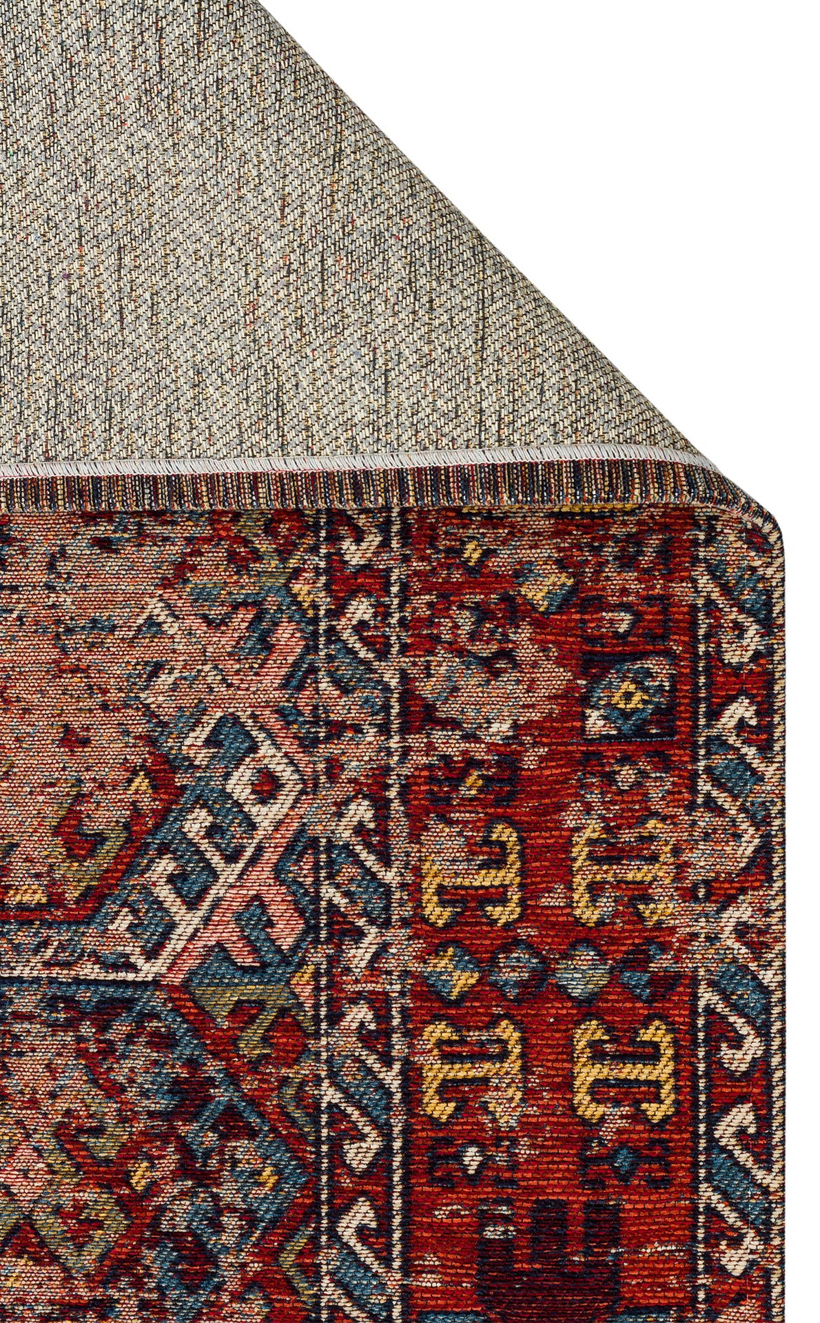 Close-up of a corner of the Nomad Spirit - Washable Kilims - AND03 rug, featuring geometric and floral patterns in red, blue, gold, and cream, with its underside folded to reveal the textured backing.