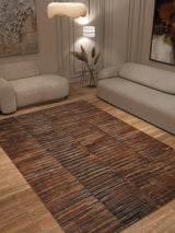 A modern living room with two beige sofas, a Nostalgic Weft - Washable Rug - JRN33 (Custom Size) in brown pattern for high-traffic areas, wooden floor, wall art, sculptural pendant light, and a decorative vase with dried grass.