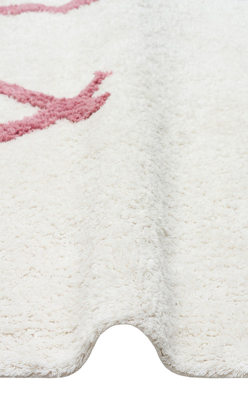 Load image 1 in gallery view. A close-up of the Nursery Nest - Washable Shaggy - CBN04 rug in cream, with a subtle wavy fold and partial pink pattern—an ultra-cozy, washable shaggy rug ideal for any nursery or living space.