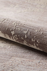 A close-up of the Old World Elegance Modern Rug - Grey - M677N reveals its soft, woven surface, machine-made quality, and subtly raised abstract texture in elegant grey tones. The rug is partially rolled to highlight its distinctive design.