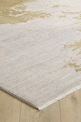 A close-up view of the Old World Elegance Modern Rug - Yellow - M677O, a machine-made rug featuring a neutral abstract pattern in beige and cream with short fringe on one edge, displayed on a light wood floor.