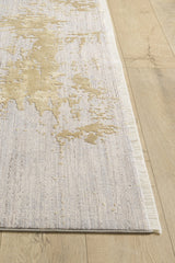 A close-up of the Old World Elegance Modern Rug - Yellow - M677O in beige, light gray, and yellowish gold abstract pattern on a light wood floor, featuring a subtle texture and thin fringe along the edge.