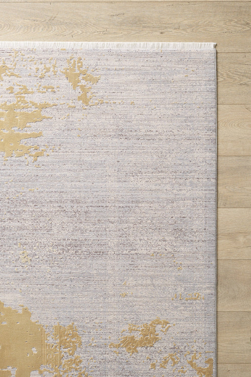 Load image 1 in gallery view. The Old World Elegance Modern Rug - Yellow - M677O, a machine-made viscose-polyester rug with a light grey, beige, and subtle gold abstract pattern plus fringe on the top edge, lies partially visible on a light wood floor.