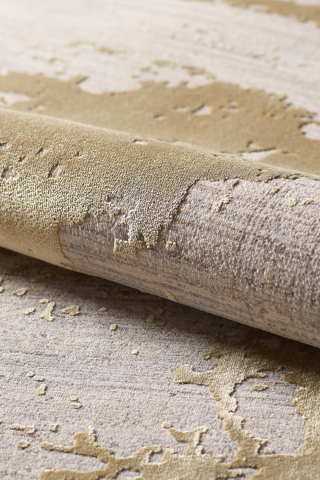 A close-up of the Old World Elegance Modern Rug - Yellow - M677O shows its machine-made, abstract gold and beige pattern with smooth and raised textures that create a shimmering, metallic effect.