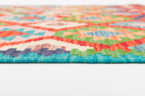 Load image 1 in gallery view. Close-up of the edge of Oriental Harmony - Handwoven Kilim, featuring colorful geometric patterns in blue, green, red, orange, and cream on a white surface.