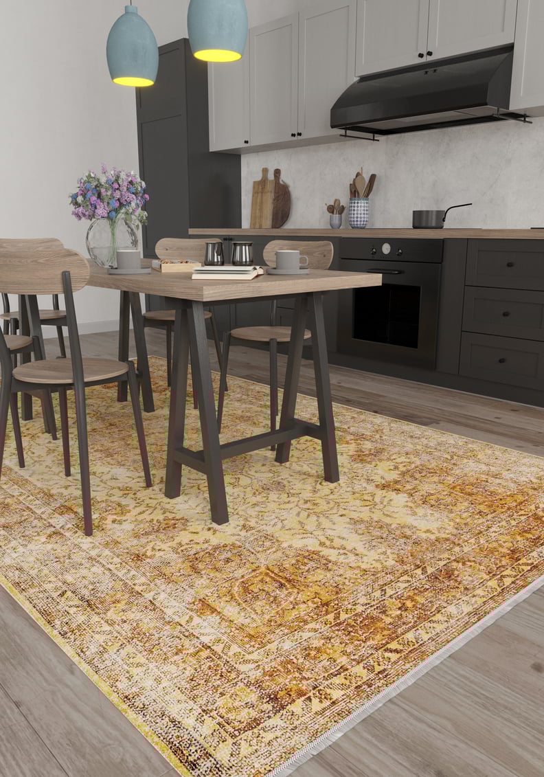 A modern kitchen with gray cabinets, a wooden dining set, pendant lights, a vase of purple flowers on the table, and the Ornate Beauty - Washable Rug - JR206 in a yellow pattern—ideal for busy, high-traffic spaces.