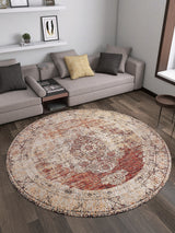 A modern living room with light gray sectional sofas, neutral cushions, wooden floors, and the Ornate Grace - Washable Rug - JR1009 in red, beige, and gold—ideal for busy spaces. Decorative shelves with books hang above the sofa.