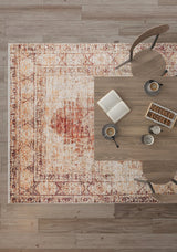 An overhead view of a wooden table with two chairs on the Ornate Grace - Washable Rug - JR1009 (Outlet) US, perfect for high-traffic areas. The table holds an open book, two coffee cups, cookies, and a small dish with a spoon on light wood flooring.