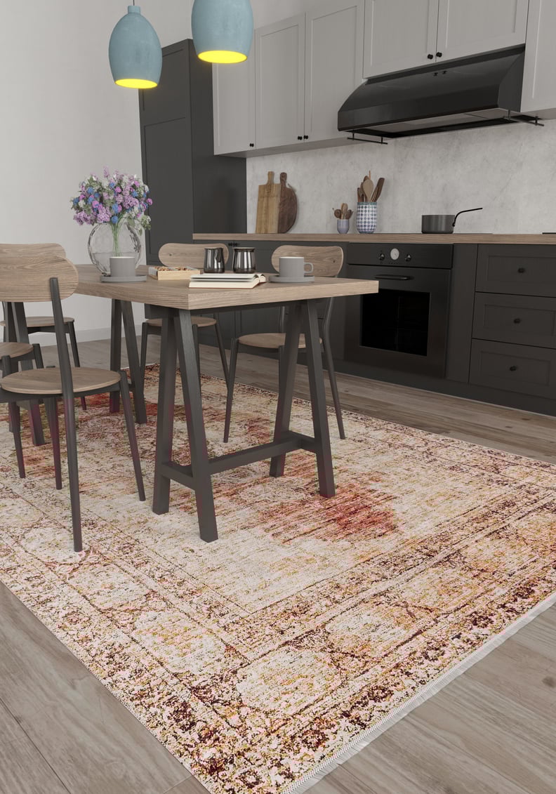 A modern kitchen with black cabinets, light wood floors, a wooden dining table and chairs, two blue pendant lights, a vase of purple flowers on the table, and the Ornate Grace - Washable Rug - JR1009 (Outlet) US ideal for high-traffic areas.