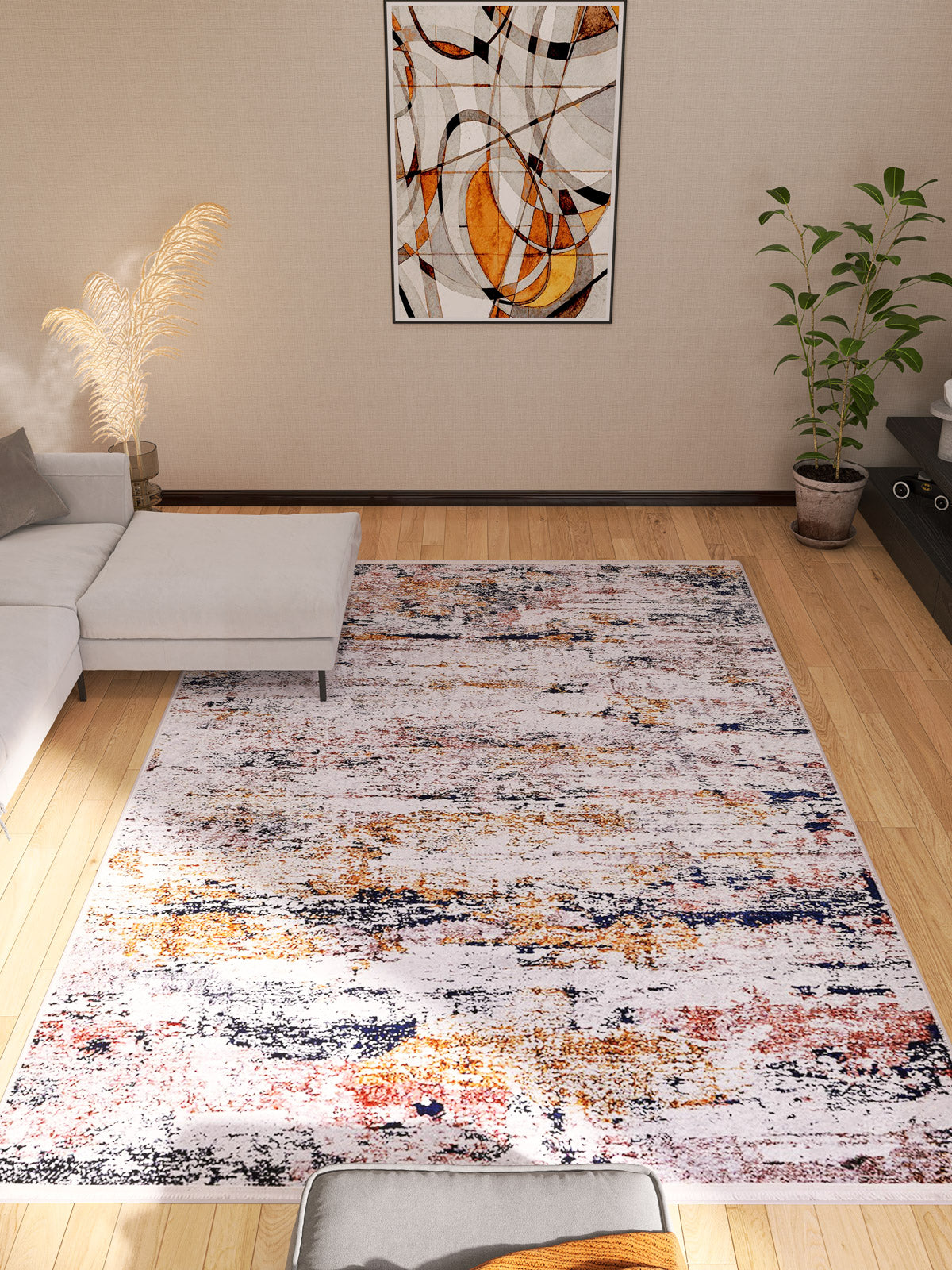 Bright living room with the Painted Dreams - Washable Rug - JR432 (Custom Size) in orange, yellow, and blue—ideal for high-traffic areas. Features a gray sectional, green potted plant, minimalist wall art, and light wood flooring.