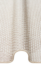 A close-up view of the Pale Shadow - Kilim - MNO03 rug in light beige, featuring a textured pattern and detailed edge stitching, partially rolled to highlight its thickness.