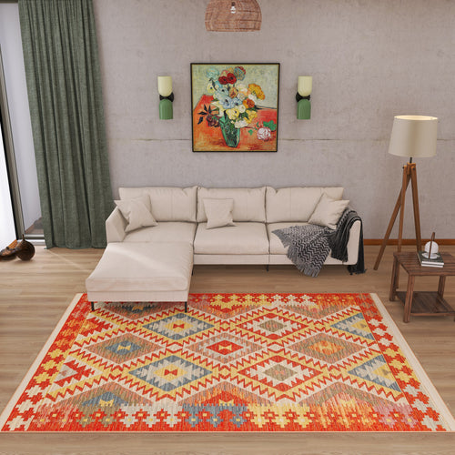 Load image 1 in gallery view. A cozy living room with a beige sectional sofa, the Pastel Grid - Washable Reversible Kilim - NMD09 rug, a floor lamp, green curtains, wall sconces, and a floral painting above the couch. A blanket is draped over the sofa’s arm.