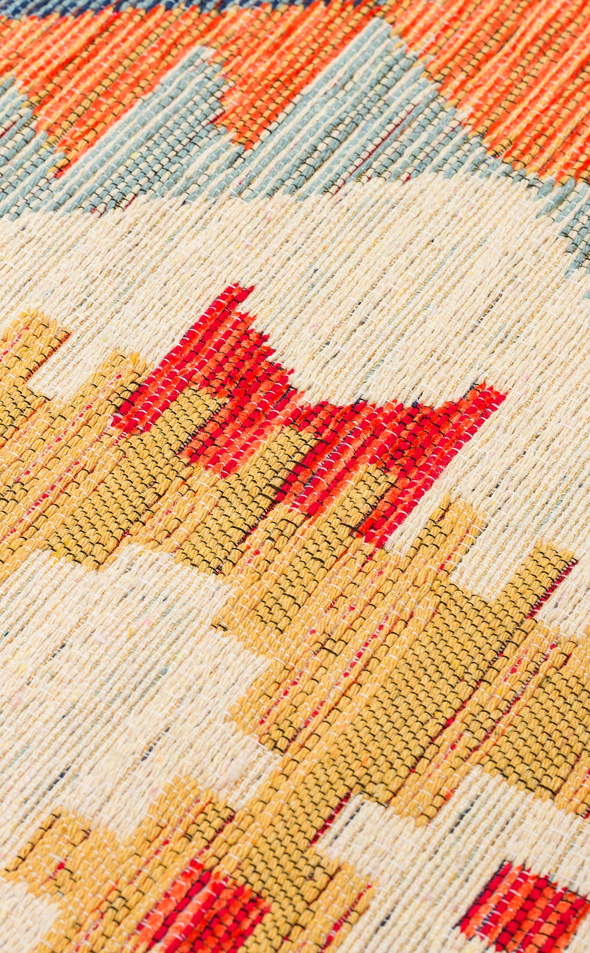 Close-up of the Pastel Grid - Kilim - NMD09 rug, showcasing red, yellow, cream, and blue geometric patterns with zigzags and angular shapes. Visible texture and threads highlight its tribal-inspired design.