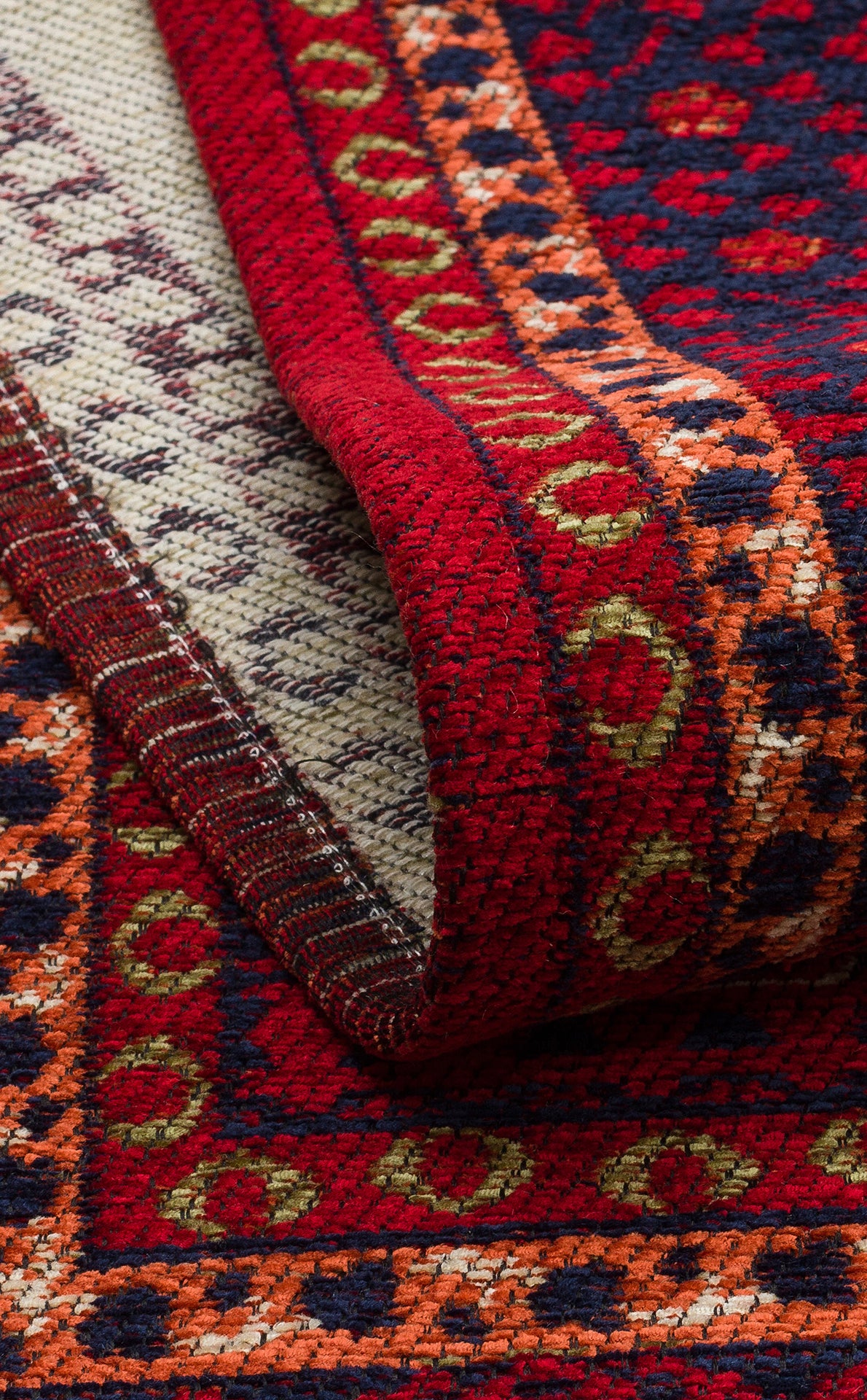 A close-up of the Patch Bloom - Kilim - BHR10 rug displays red, orange, yellow, navy, and cream geometric and circular patterns with a folded corner showing its underside.