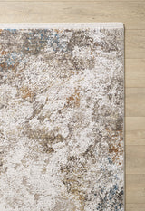A close-up of the Pebble Pathway Premium Area Rug - M683L, featuring a machine-made abstract speckled pattern in white, beige, brown, and gray, showcased on a light wood floor.