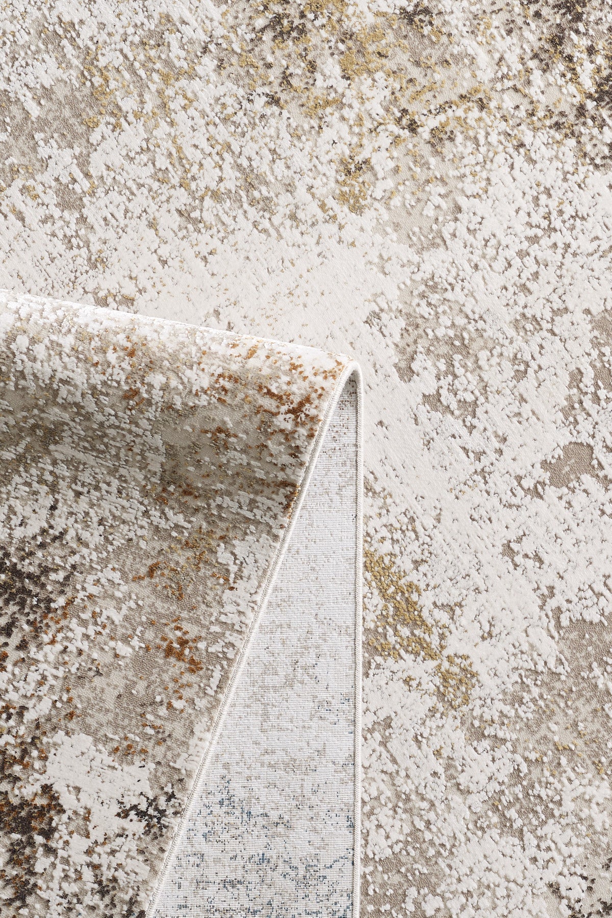 A close-up of the Pebble Pathway Premium Area Rug - M683L shows a beige and cream base with a mottled abstract pattern in brown, gold, and gray hues; one corner is folded to display the underside.