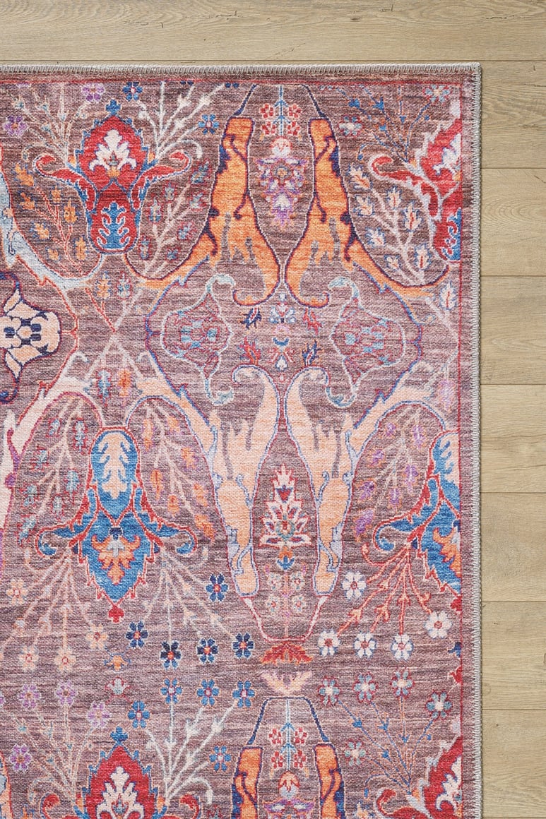 The corner of the Peregrine Peachy Brown Washable Rug - LCC3022 (Custom Size), featuring colorful floral and abstract patterns in red, blue, orange, and purple, lies on a light wood floor—ideal for high-traffic areas.