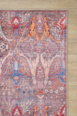 The corner of the Peregrine Peachy Brown Washable Rug - LCC3022 (Custom Size), featuring colorful floral and abstract patterns in red, blue, orange, and purple, lies on a light wood floor—ideal for high-traffic areas.