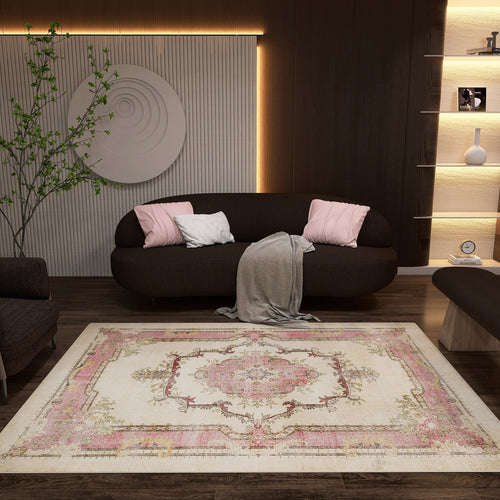 Load image 1 in gallery view. A cozy living room with a dark sofa, pink and white cushions, and a gray throw. The Petal Mist - Washable Rug - JRS025 with a pink and beige geometric pattern brightens the wooden floor. Shelves, soft lighting, wall art, and a plant complete the look.